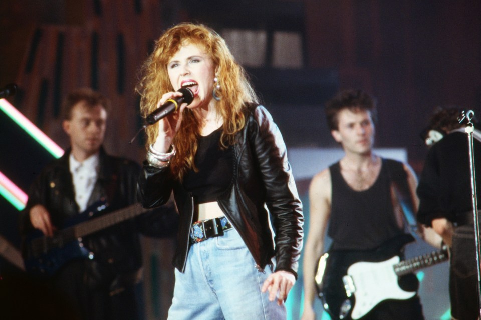 Carol Decker of T'Pau singing into a microphone on stage.