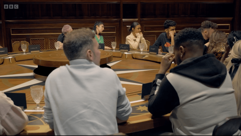 The Traitors season 3 contestants seated around a large round table.