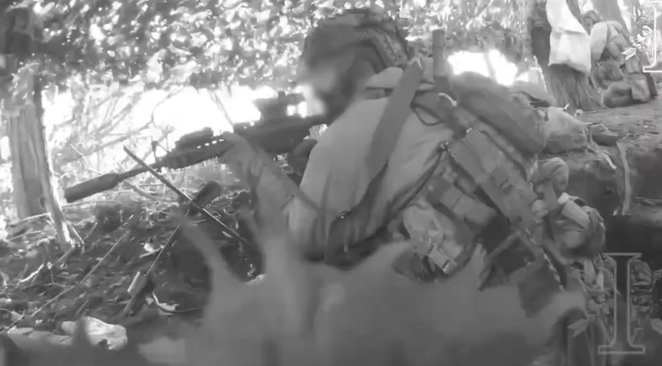 Black and white image of a soldier aiming a rifle in a trench.