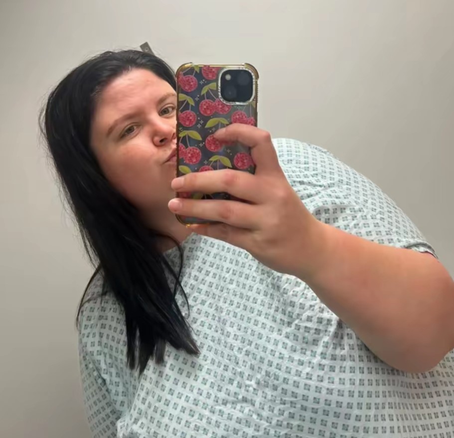 Woman in hospital gown taking a selfie.