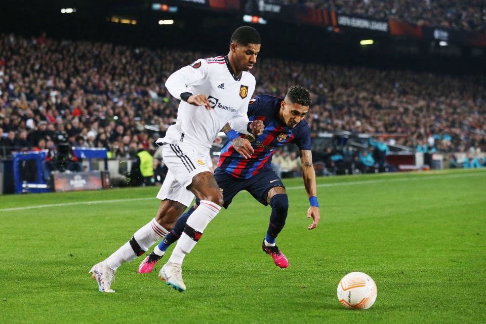 Marcus Rashford of Manchester United and a Barcelona player vying for the ball during a soccer match.