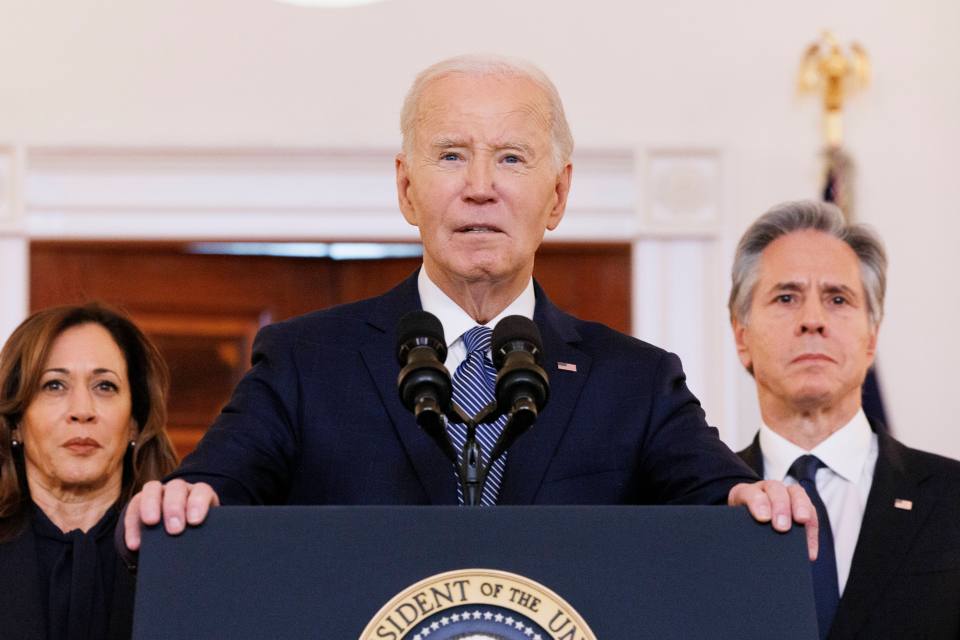 President Biden speaks at a podium with Kamala Harris and Antony Blinken.