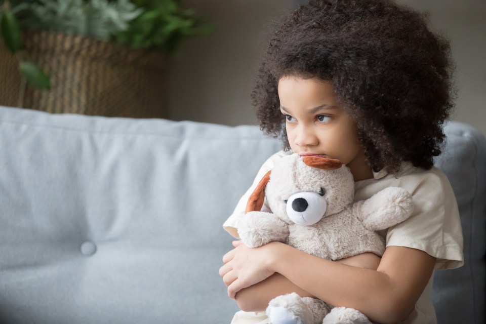 Sad young girl hugging a stuffed animal.