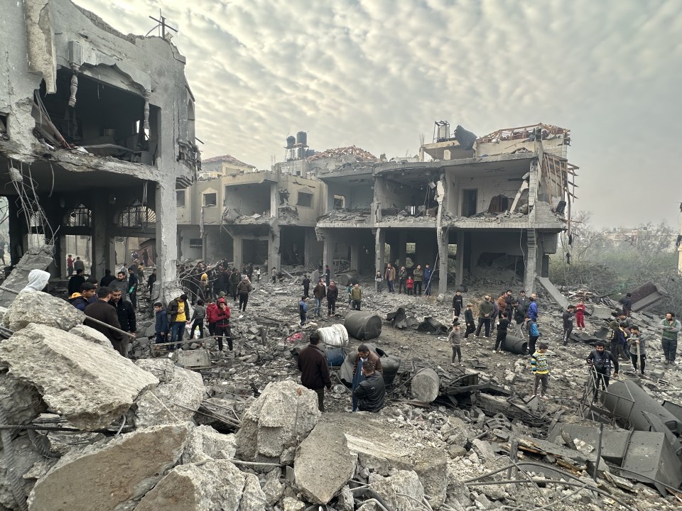 Aerial view of a destroyed residential building in Gaza, with people surveying the damage.