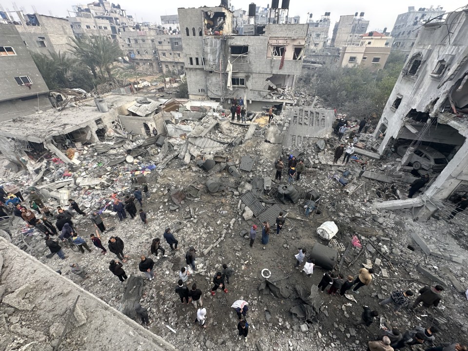 Aerial view of a destroyed residential building in Gaza, with people surveying the damage.