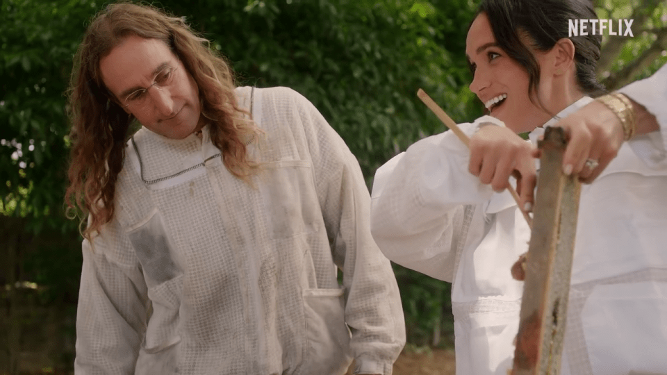 Meghan Markle and a beekeeper inspecting a honeycomb.