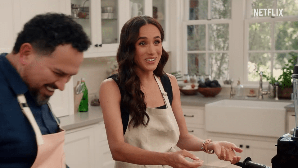 Meghan Markle and a man laughing in a kitchen.