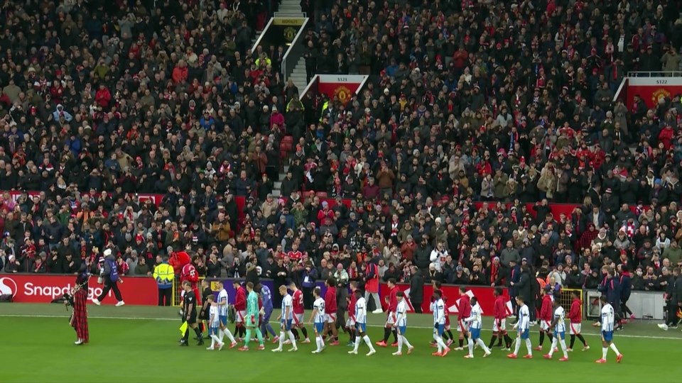 Soccer teams entering the field in front of a large crowd.