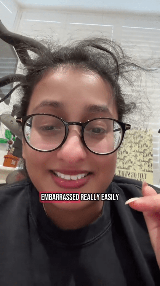 Close-up of a woman wearing glasses, smiling and saying she's easily embarrassed.