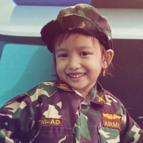 Photo of a young girl in a camouflage uniform smiling.