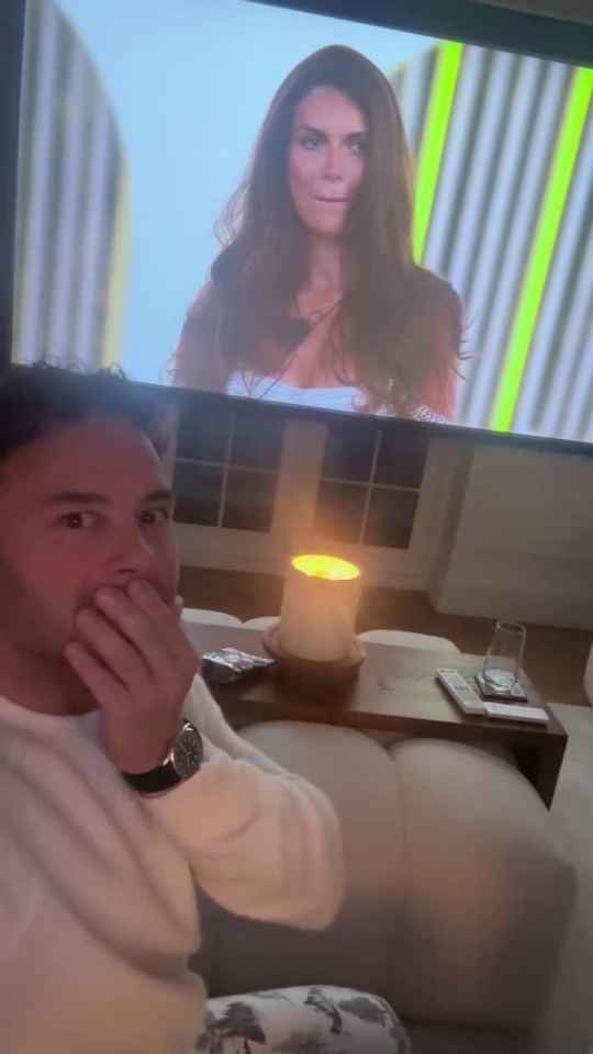 Man reacting in shock while watching a woman on TV.