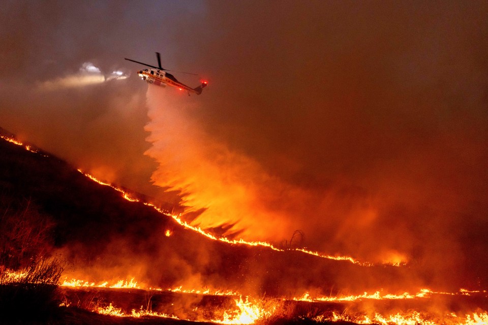 Helicopter dropping water on a wildfire.