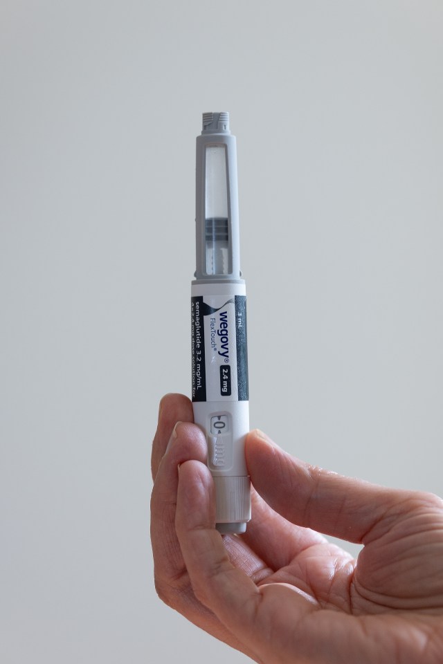 A hand holding a Wegovy injection pen.