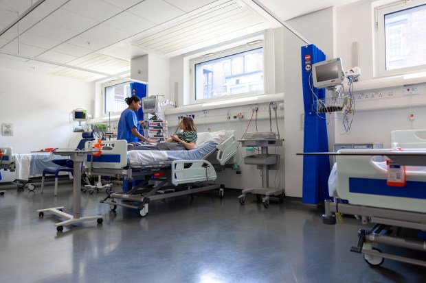 A nurse takes a patient's vital signs in a hospital room.