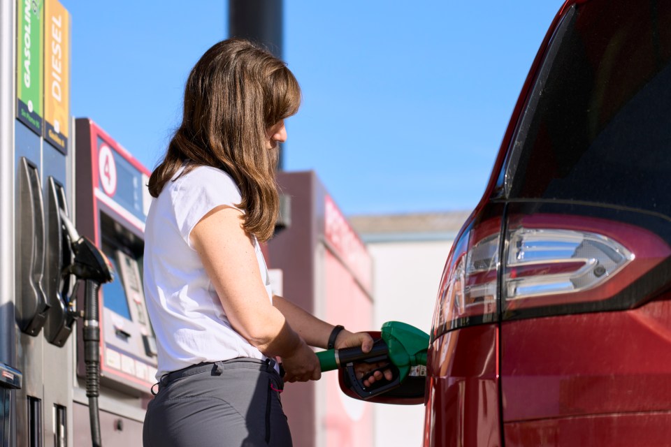 Woman smiling while filling her car with gas at a gas station.