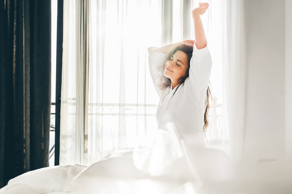 Woman waking up in bed and stretching.