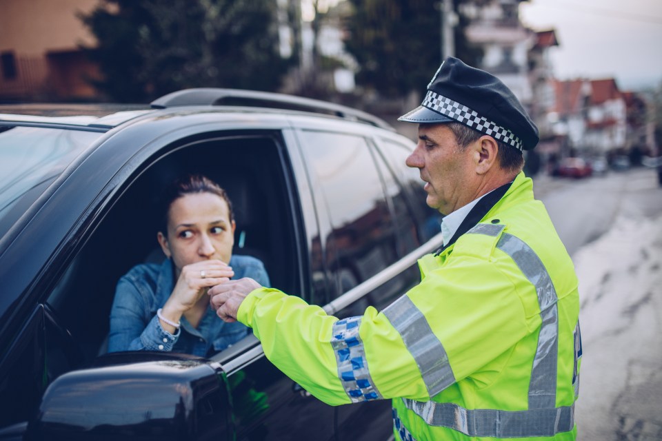 Woman taking a breathalyzer test from a police officer.