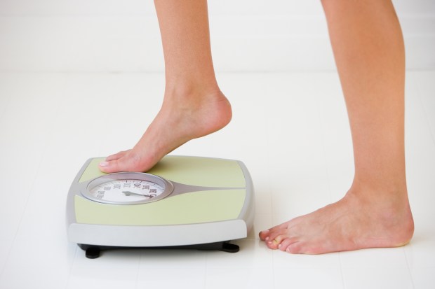 Woman stepping onto a bathroom scale.