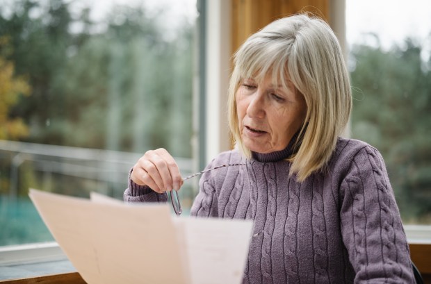 A senior woman looks worried as she examines an energy bill.