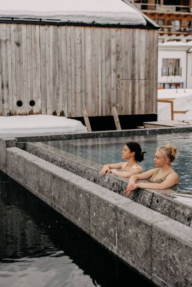 Two women relaxing in an outdoor pool.