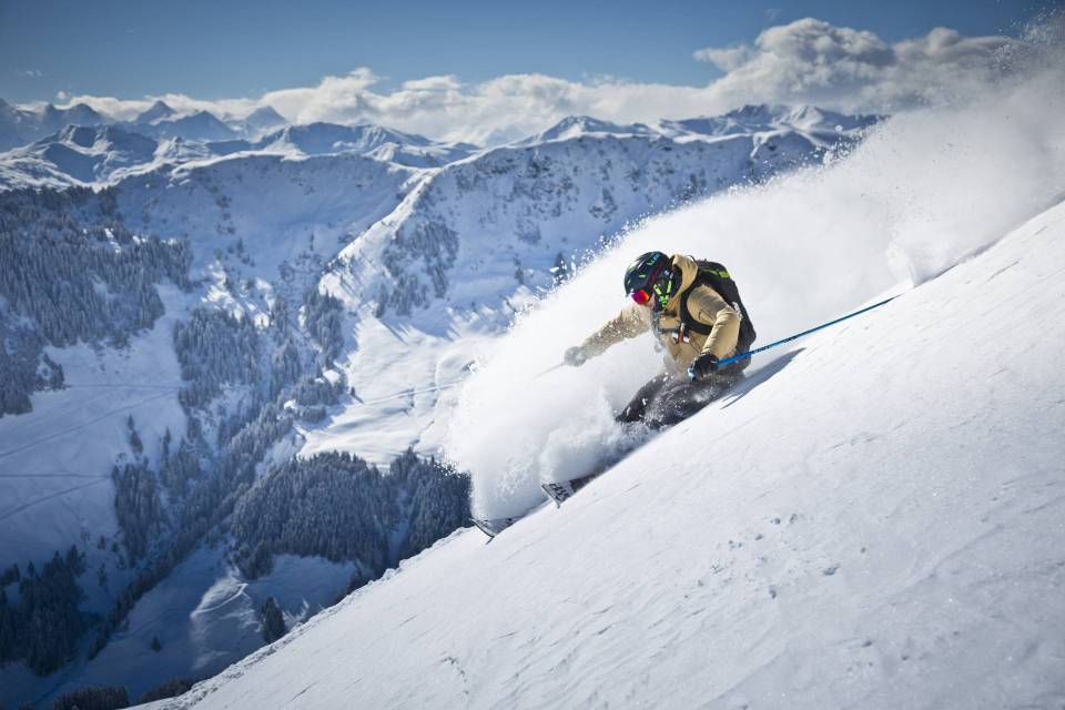 Skier carving down a snowy mountain slope.