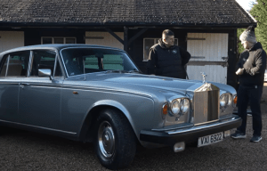 Silver Rolls-Royce Silver Shadow with two men standing beside it.