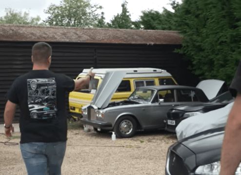 Man pointing at a Rolls-Royce in a barn.