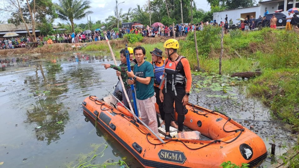 Rescue workers in a boat search a lake after a girl was killed by a crocodile.